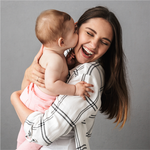 Joyful mother cradling her baby wrapped in a striped blanket, both laughing